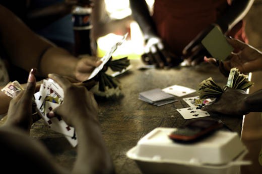 Due to Jamaica's high unemployment rate most young people are left with a lot of time on their hands. On days when there isn’t much else to do, residents gather on the front porch of a burnt out abandoned house called “the gambling house”. Here a group of young women are playing for a chance to win.