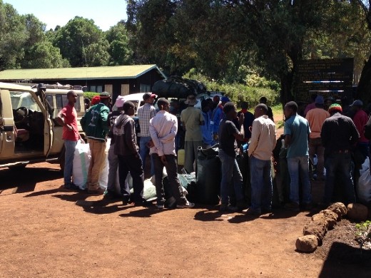 At the Londrossi Gate all of the porters gather around a scale to weigh the bags. In the past there were no regulations and porters were expected to carry a ridiculous amount of weight without proper clothing or footwear.  Fortunately now there are better regulations with a maximum of 50 pounds per porter and the Kili Porters Assistance Program lends them proper gear to make the climb.  Our outfitter, SENE, is well known for treating/paying their porters well ... one of the reasons I chose them! :-) 