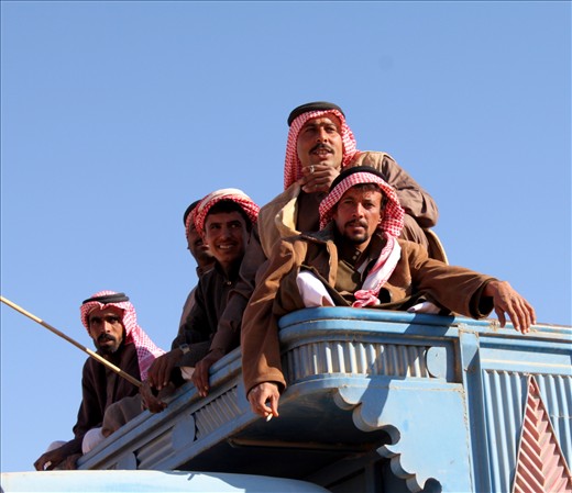 We unexpectedly encounter a Camel Beauty Contest taking place in the desert. These men are arriving with their camels for the competition. 