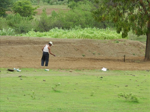 A farmer is working on farm after rain to grow something