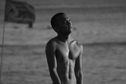 A balinese man catches his breath staring at the sunset, during a beach soccer match in Bali, Indonesia.