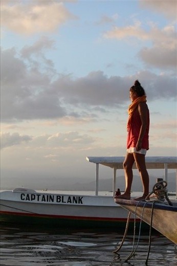 Lady awaits fot the sunset on the prow of a boat, in the shore of Lembongan island, Indonesia.