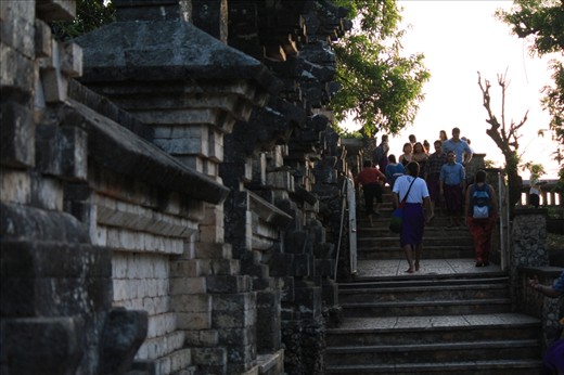 Man walks around the ancient Uluwatu buddhist temple built on a cliff to the ocean in Bali, Indonesia.