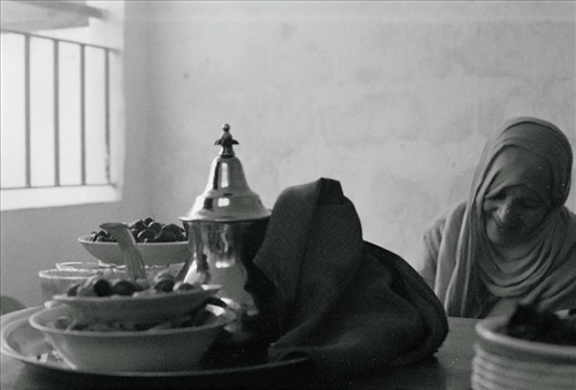 My host mother grills pieces of ram heart on charcoal coals for the Eid lunch that sits on the table. Eid al Adha is a holiday to celebrate life and community.  Dates, olives, 