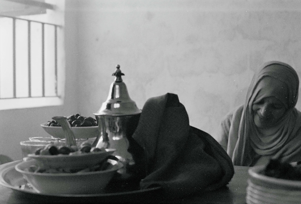 My host mother grills pieces of ram heart on charcoal coals for the Eid lunch that sits on the table. Eid al Adha is a holiday to celebrate life and community.  Dates, olives, 