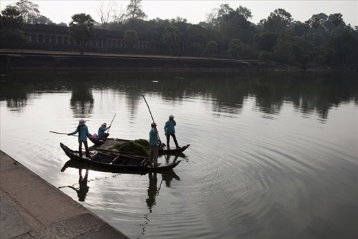 Groundskeepers make their way across the waters that surround the temple. This ancient moat structure, excavated by hundreds of thousands of workers, is so big that it’s visible from space.