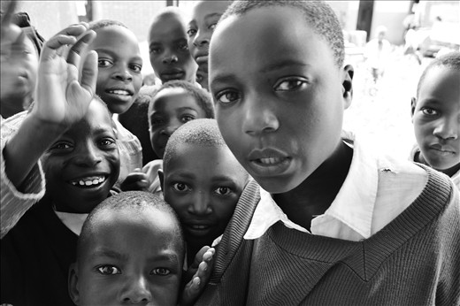Inquisitive. Looking through a window I see a group of children huddled outside, curious to know what we are doing in their old school classroom.
