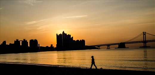 A Korean woman enjoys the sunrise solitude of gwangalli beach in Busan.