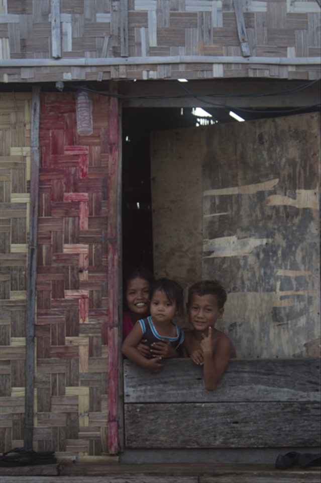 Children on Sampella wave and smile to get their photos taken by visitors.