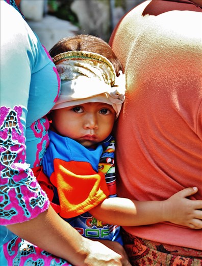 A child seated between his parents on a motorbike in Bali.