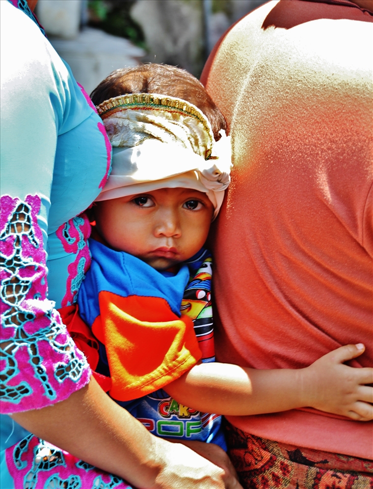 A child seated between his parents on a motorbike in Bali.