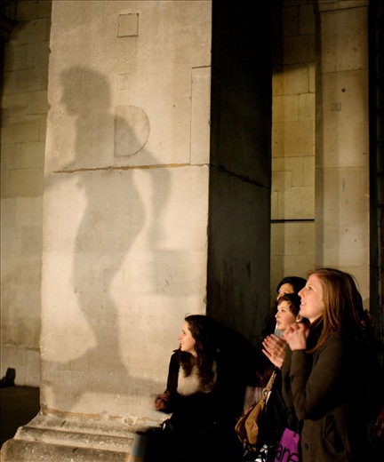 A street performer in Stockholm is silhouetted as onlookers stare, transfixed. 