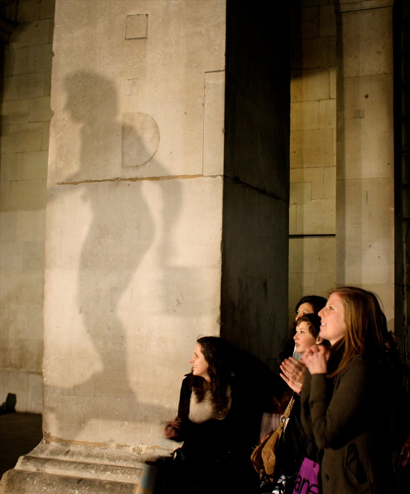A street performer in Stockholm is silhouetted as onlookers stare, transfixed. 