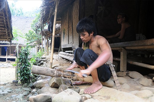 A Baduy boy sharping his tools after a days work in the fields.