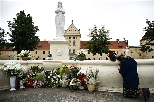 An old woman prays to the Mother of God statue. 