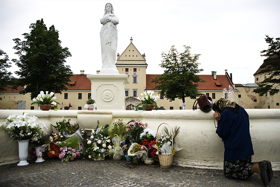 An old woman prays to the Mother of God statue. 