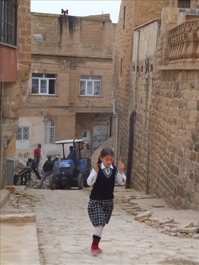 A city in the midst of restoration and a girl skipping towards education.