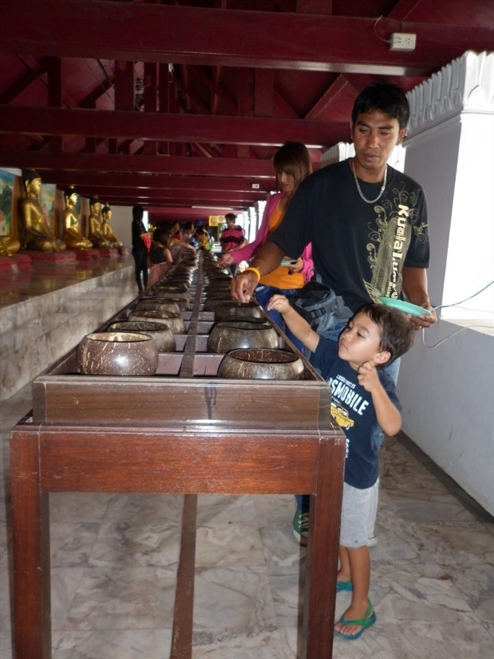 Father & son putting coin offerings for Buddha.