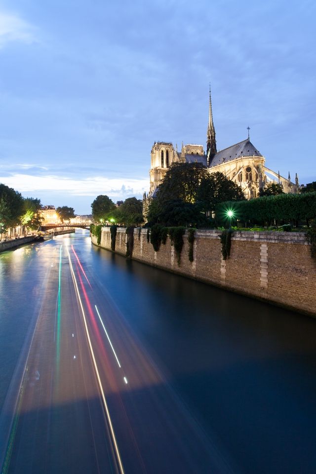 Notre Dame with the streaks of a riverboat cruising down the Seine.