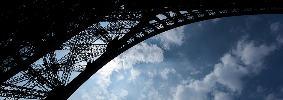 Detail of the Eiffel Tower's latticework silhouetted by the afternoon sky