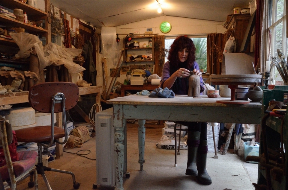 Inside the studio. Putting her hands in clay and creating something from the earth allows Heather to drift away. She does not use potter wheels as she feels it disconnects her from the clay she is sculpting. A radio mumbles monotonously in the background. 