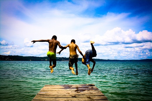 Leap of faith:
In between the moments of hardships to keep their families well-fed and cared for, people of Bolivia have learnt to derive pleasures from very small things in life. I saw Juan, Aleron and Cassius (L-R) playing around at the shore of Lake Titicaca. I asked these friendly kids to jump from the boardwalk while I capture their jump from behind and they enthusiastically agreed. I think this picture is an ultimate expression of human joy: the vibrant colors of the sky and the water are a perfect backdrop to the care-free attitude of the kids in spite of having just entered an intimidating world of adversities.
NB: For continuation of my story, please take this as photo # 5. (I could not change the order of the photos)