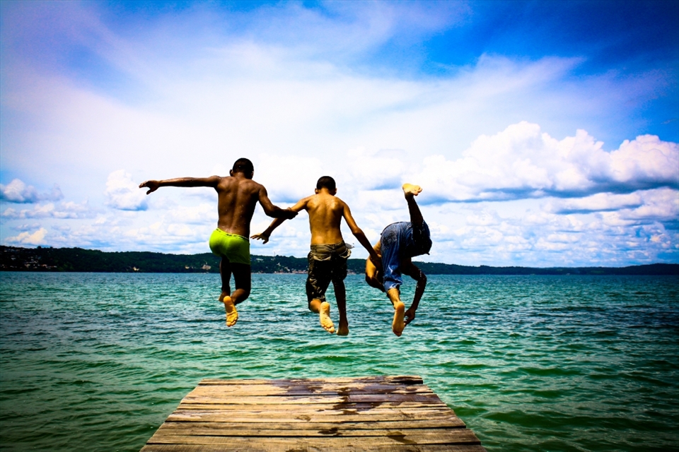 Leap of faith:
In between the moments of hardships to keep their families well-fed and cared for, people of Bolivia have learnt to derive pleasures from very small things in life. I saw Juan, Aleron and Cassius (L-R) playing around at the shore of Lake Titicaca. I asked these friendly kids to jump from the boardwalk while I capture their jump from behind and they enthusiastically agreed. I think this picture is an ultimate expression of human joy: the vibrant colors of the sky and the water are a perfect backdrop to the care-free attitude of the kids in spite of having just entered an intimidating world of adversities.
NB: For continuation of my story, please take this as photo # 5. (I could not change the order of the photos)