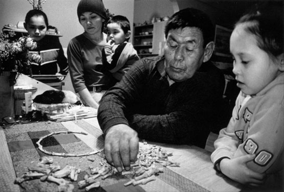 With the bones of a seal flipper,
Abraham Arnaqaq shows his daughter and grandchildren traditional Inuit games that were played when he was a child. Pangnirtung, Nunavut. 