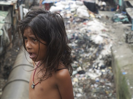 This child lives in a hut beside a mountain of putrid garbage and toxic water