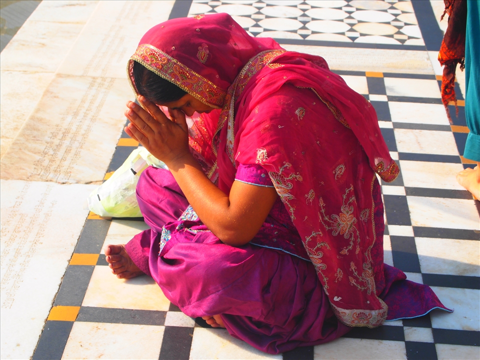 Seeking Spiritual Solace. A pilgrim deep in prayer beside the pool. Everybody, irrespective of cast, creed, race or religion can join the experience in this spiritual place.