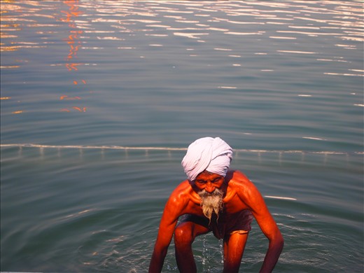 Emerging from The Pool of Nectar. An elderly pilgrim climbs out of the sacred pool after a ritual bath.