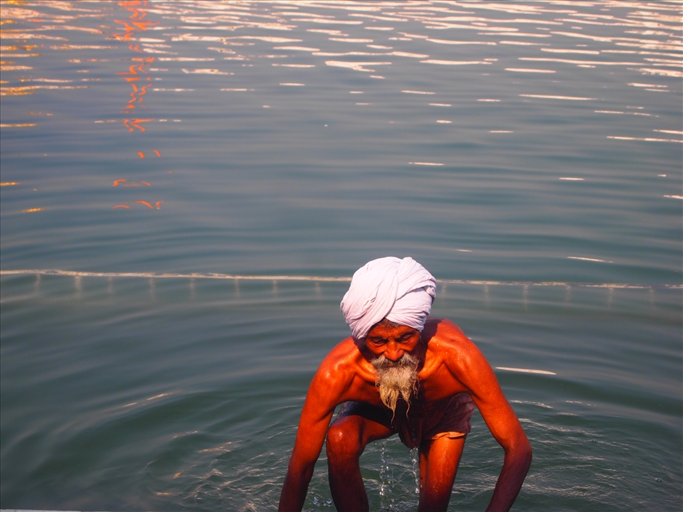 Emerging from The Pool of Nectar. An elderly pilgrim climbs out of the sacred pool after a ritual bath.