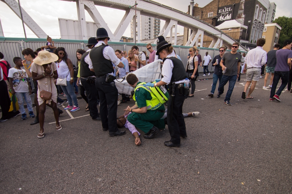 Police and a paramedic prepare to cover what appears to be an unconscious man