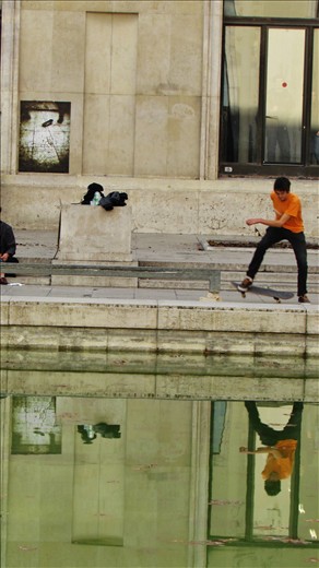 A boy skating in front of the  musée d'art moderne de la ville de Paris.