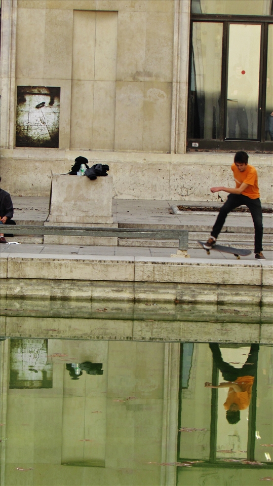 A boy skating in front of the  musée d'art moderne de la ville de Paris.