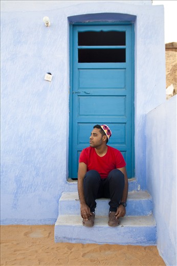 a nubian man wearing the traditional hat sitting on the roof of a nubian house