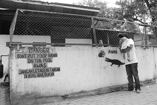 A man with little girl look at the crocodiles in the inside of crocodile cage in Asam Kumbang Crocodile Park.