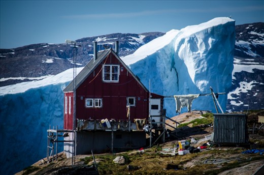 In Northern Greenland there is a village close to Upernavik which has gigantic icebergs close to it every year; the village is called Innaarsuit.
I went there not sol long ago with my dad when I heard about the iceberg and found a good spot to use the house as a background.
I really like the details here; the house is a very common hunter house nowadays, as you can see there is a polar bear skin hanging outside and there is bunches of equipments by the hunter who lives in the house. In addition there is a bird which is on the top of the iceberg on the right side which also caught my attention. I really love to mix up lots of different color sometimes, as you can see here. I