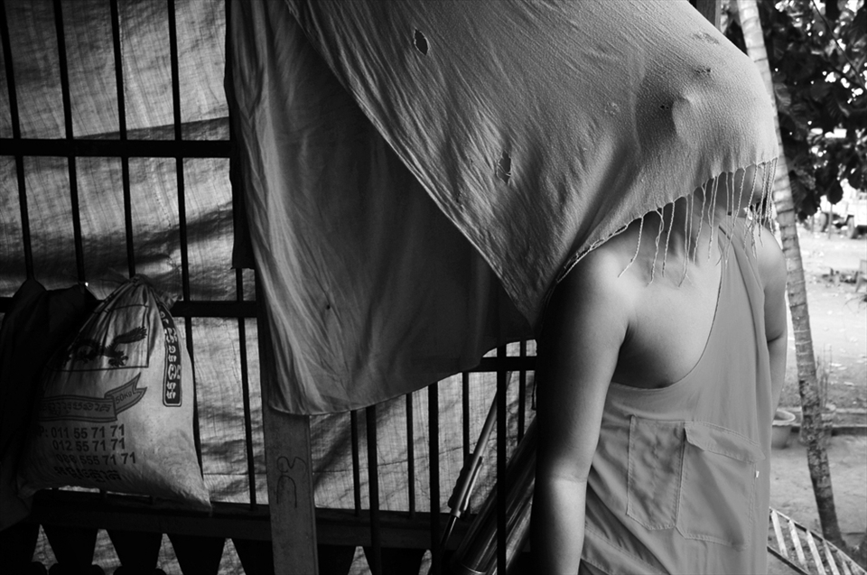 Cambodian monk looks through the scarf hiding his face from the daylight