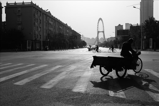 Men on bicycles cycling cross a junction with the large ‘Tianjin Eye’ looming in the background. This picture has elements of the old and new coexisting and a feeling of movement. Can China manage to move in a direction that successfully balances traditional values and the demands of a newly industrialised country?    
