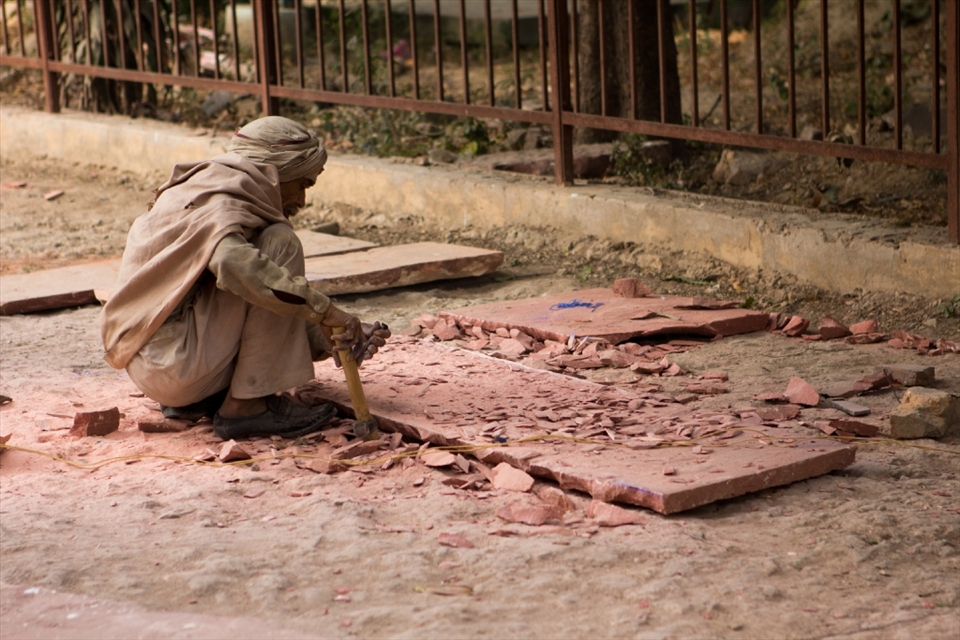 A man uses native techniques to chisel a stone tile to be used for a walkway in the Red Fort, Delhi