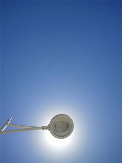 This photo I took when I was lying down in Balneário Camboriu´s harbor in Brazil. I realized it was a very interesting scene, a lamppost doing the exact opposit work, protecting me from the strong though natural light of the sun.