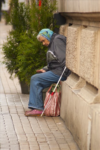 Old woman asks for money and looking for warmth from the window of a kitchen 
