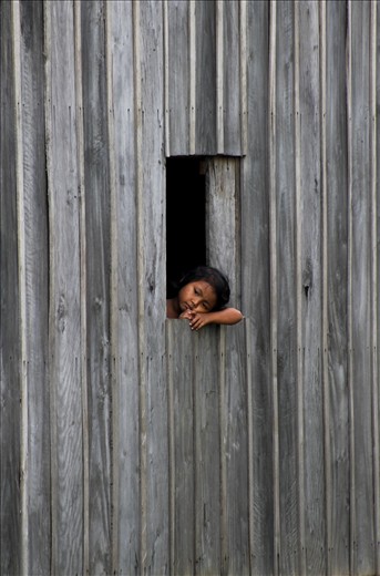'thoughts' - taken in the small rural town of Kampot, South Cambodia. A young girl seems far away in thought, resting, looking out her home window into the rice fields. What is she thinking of...?