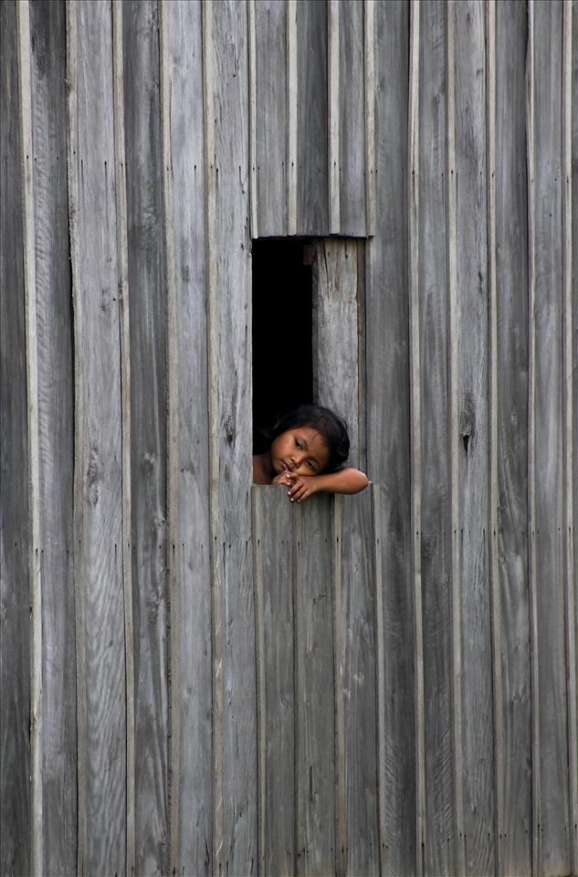 'thoughts' - taken in the small rural town of Kampot, South Cambodia. A young girl seems far away in thought, resting, looking out her home window into the rice fields. What is she thinking of...?