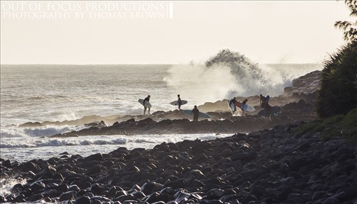 Surfers line up to jump out whilst some retreat from the rough sea's.