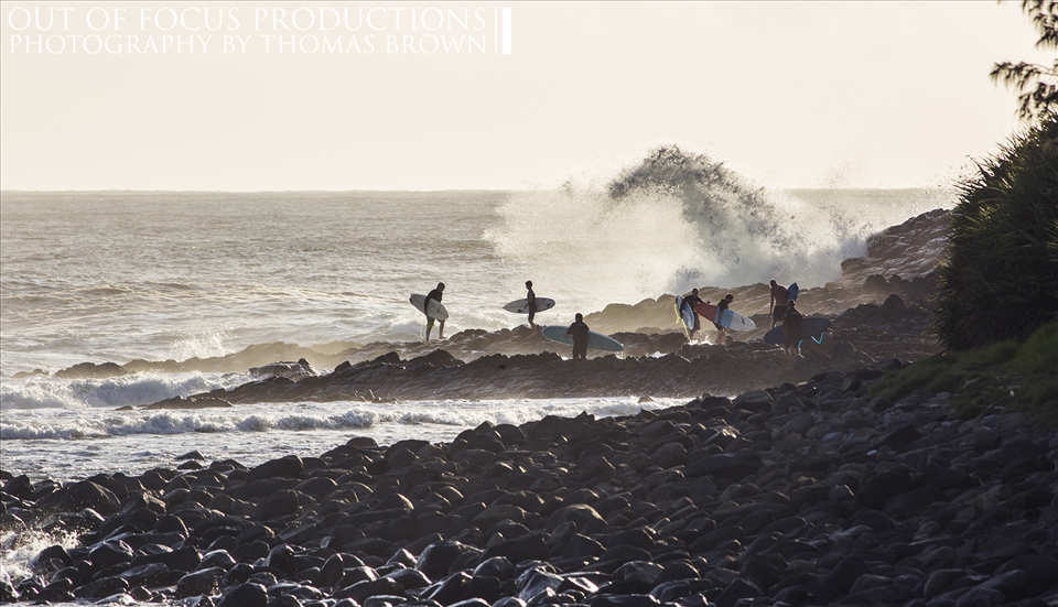 Surfers line up to jump out whilst some retreat from the rough sea's.