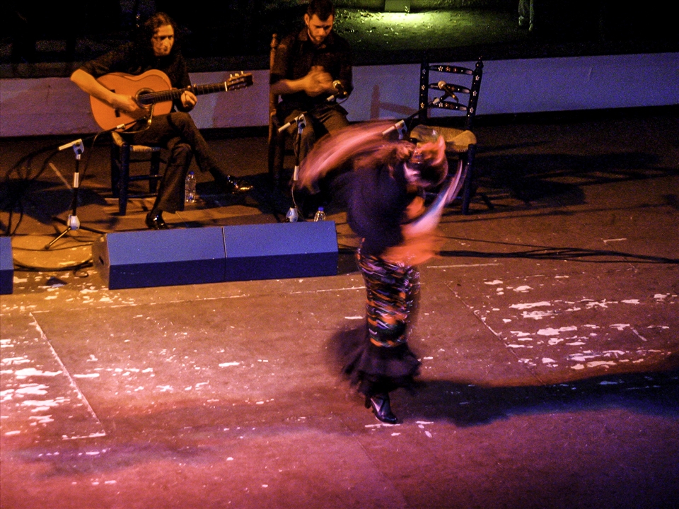At a professional flamenco show, a dancer tells her story through the music & fluid rapid movements. Female flamenco dancers come across as strong proud individuals, like a female equivalent of a Torero (Bullfighter)