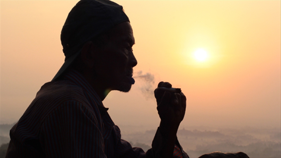 Setumbu Hill sunrise, old man smoking traditional corn leaf javanese cigarette