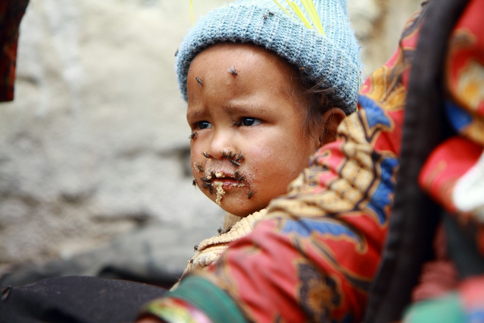Undisturbed - Bajhang district in far western Nepal is gripped with recurring food insecurity and rampant poverty. The village is infested with flies to the point that no one bothers to get rid of them anymore. This small child stares helplessly as his face is being plagued with flies.